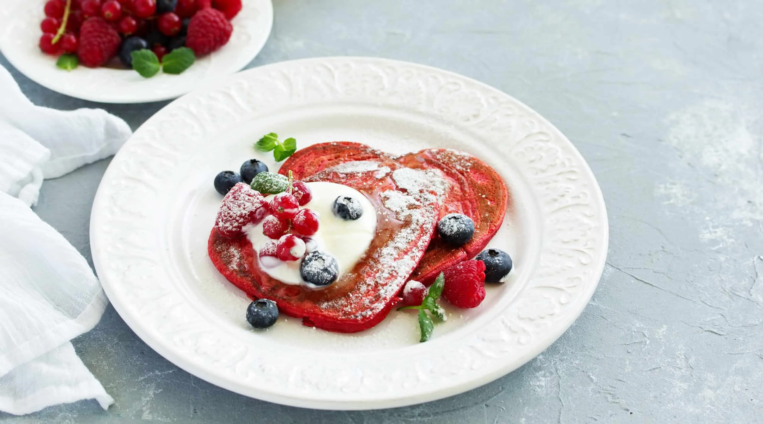 Pancakes red velvet in the form of a heart with berries and cream. Valentine’s Day. Selective focus.
